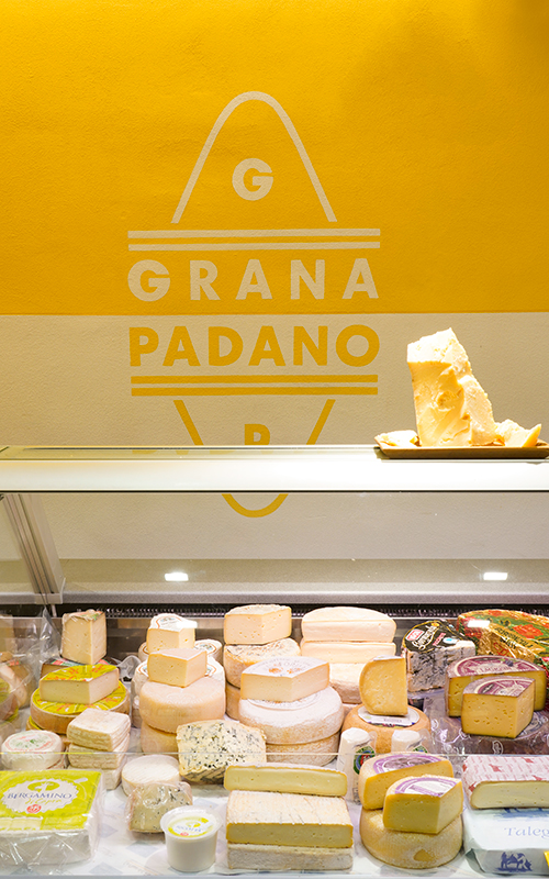 sezione banco frigo con formaggi e logo grana padano sul muro